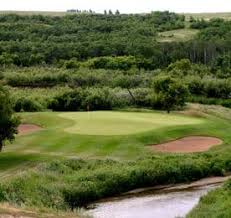 A protected green tucked between bunkers and prairie coulee at a Canadian golf course